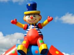 Alquiler de Castillos Hinchables: Diversión Garantizada para Cualquier Evento A vibrant inflatable clown at an outdoor carnival under a bright blue sky, symbolizing fun and joy.