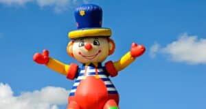 Alquiler de Castillos Hinchables: Diversión Garantizada para Cualquier Evento A vibrant inflatable clown at an outdoor carnival under a bright blue sky, symbolizing fun and joy.