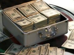 Qué es el crowdlending y cómo funciona esta alternativa financiera Open briefcase filled with stacks of hundred dollar bills on a glass table, representing wealth.