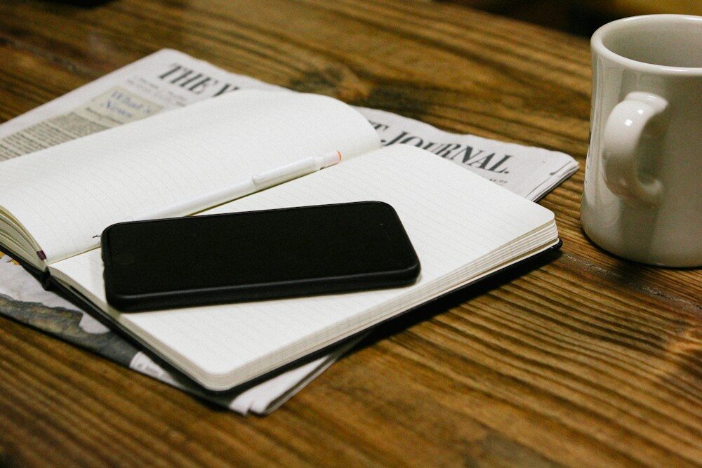 Escritorio con cuaderno, móvil y papeles